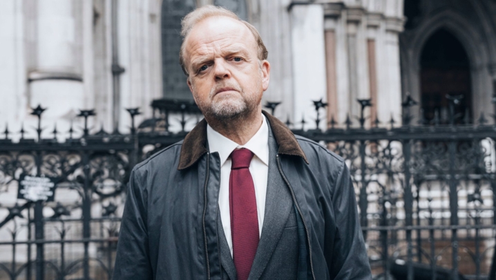 Toby Jones, as Alan Bates, stands outside the Royal Courts of Justice