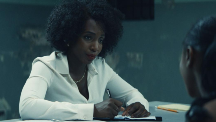 Tamara Lawrance sits in a police interrogation room, looking at a suspect, of whom all we see is the back of their head