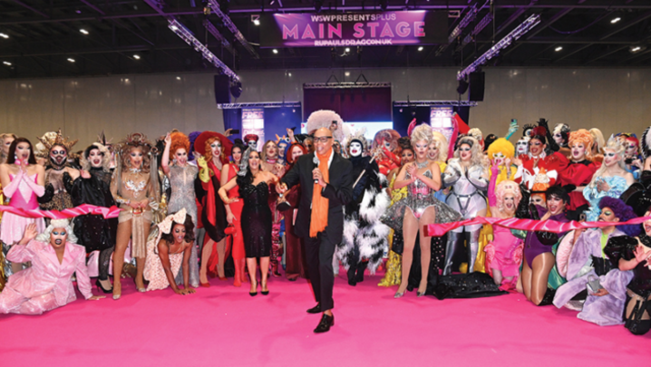 RuPaul stands in front of a group of drag queens at DragCon UK