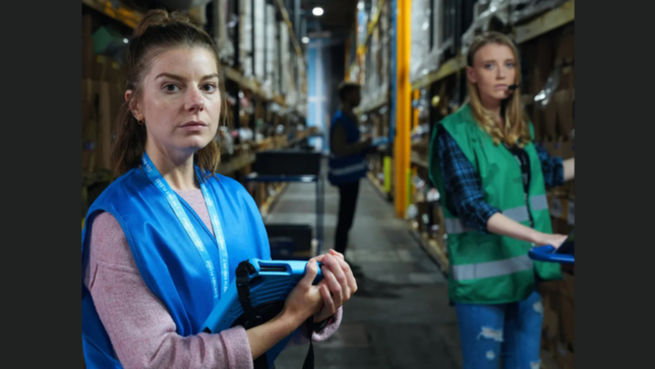 two women in high vis jackets stood near industrial shelving