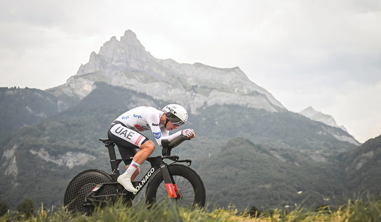 A professional cyclist rides the Tour de France for Team UAE against a mountainous backdrop