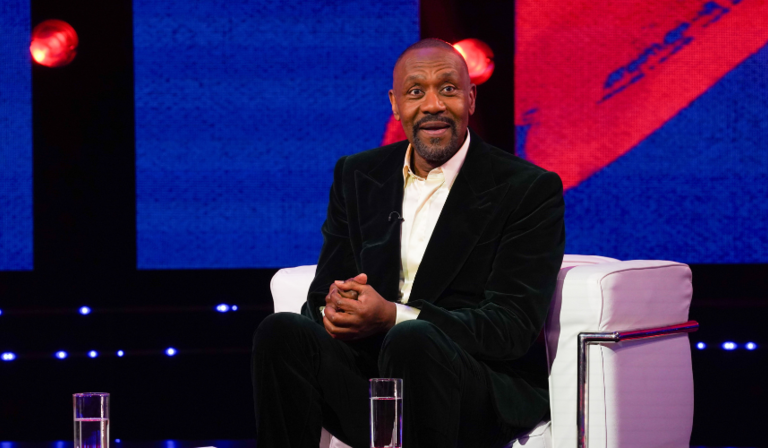 Lenny Henry sits down in a TV studio, looking off camera