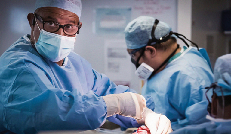 Two surgeons in the middle of operating, one in focus and the other out of focus