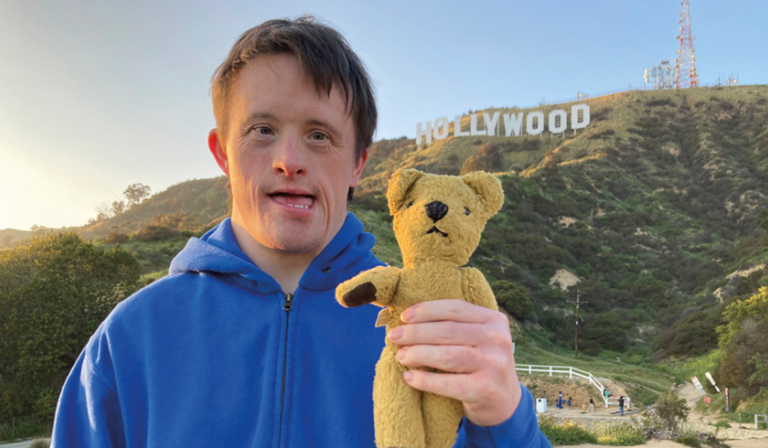 Tommy Jessop holds a stuffed bear, standing by the Hollywood sign in Los Angeles