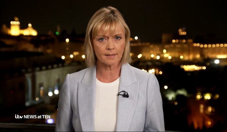 Julie Etchingham stands in front of a blurred outdoor backdrop at night, the ITV News at Ten logo superimposed in the bottom left corner