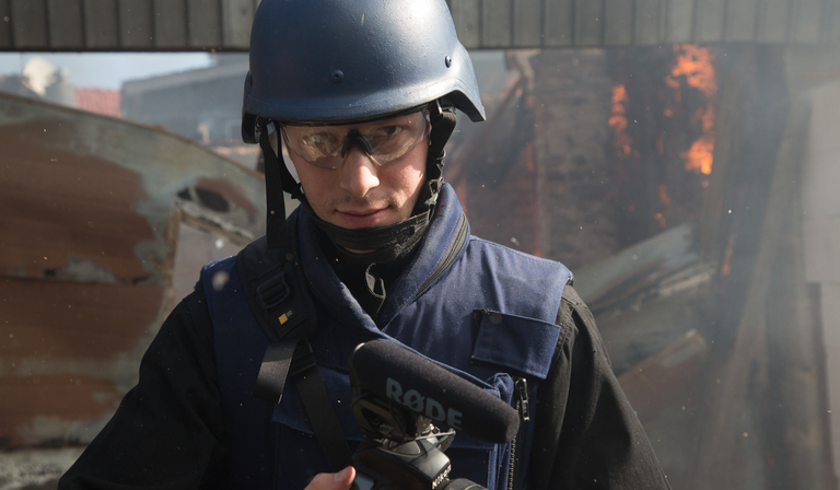 A reporter wears a body armour vest and helmet 