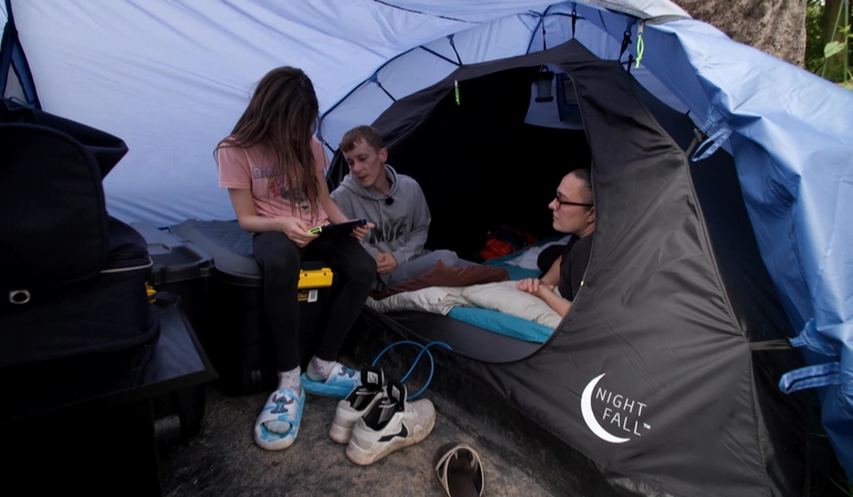 Three people are in a medium-sized tent