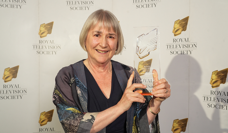 Gwyneth Hughes stands holding her RTS Yorkshire award trophy