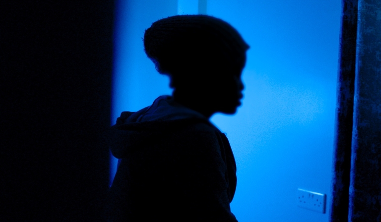 A person is silhouetted against a wall basked in blue light