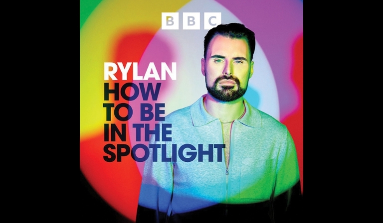 Rylan stands in front of multicoloured lights, the BBC logo above him and text reading "RYLAN: HOW TO BE IN THE SPOTLIGHT" to his left